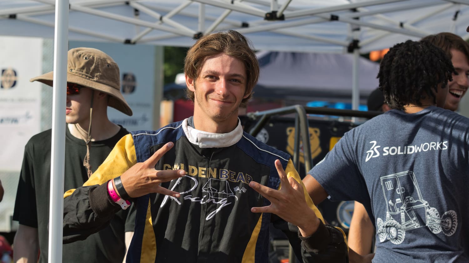 A driver in race suit celebrating with teammates before a run