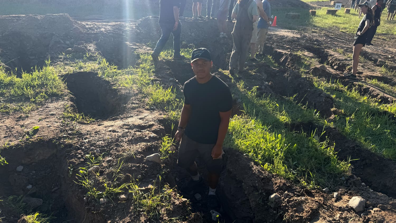 A team member standing in a deep rut on the course, showing how rough the terrain is